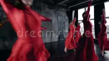精力充沛的年轻女孩穿着红色舞蹈服装，在黑墙的工作室里表演集体舞。
